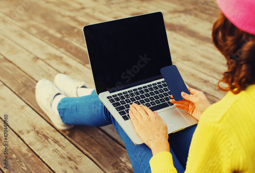 Close up woman working with laptop and smartphone on wooden table or floor background, black screen, top view