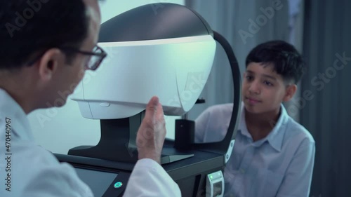Boy doing eye test checking examination with autorefractor in optical shop, Optometrist doing sight testing for child patient, Eye doctor examinating kid patient