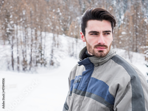 Handsome man standing in snow with ski suit