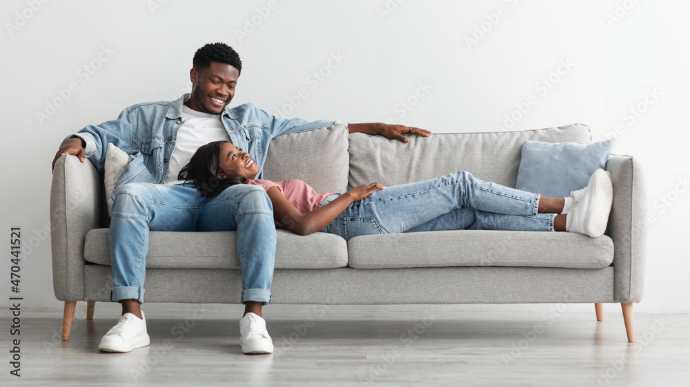 African american couple spending weekend together lying on couch