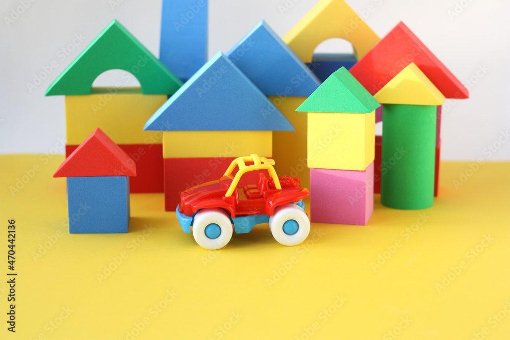Toy red car on a background of multi-colored cubes. Educational game for young children. Yellow background.