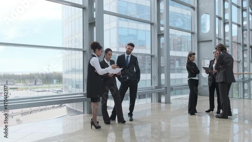 Business people talking about documents in office lobby of modern building