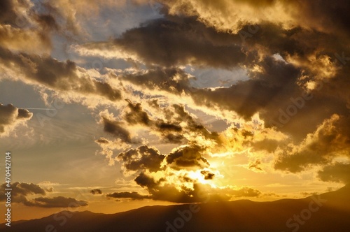 Colorful clouds scape sunset over City and sea.Sun breaking through clouds at sunset. Red sky over hill and mountains. Dramatic heaven. Travel concept © Marilena