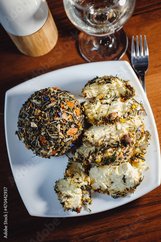 Konstfotografi French spicy Boulette d'Avesnes cheese, sprinkled with various herbs, lies on a white plate, closeup