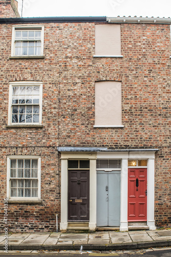 Facade of traditional British brick terraced houses with colorful doors in York England