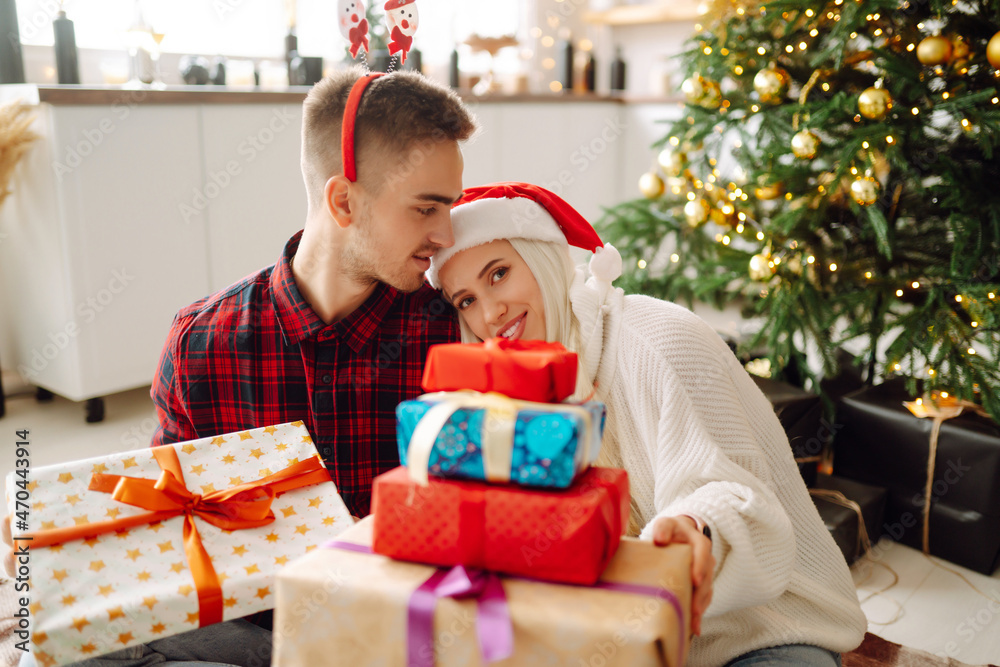 A loving happy young couple enjoying time together near Christmas tree. Romantic day. Winter holidays.
