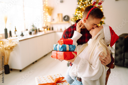 A loving happy young couple enjoying time together near Christmas tree. Romantic day. Winter holidays.