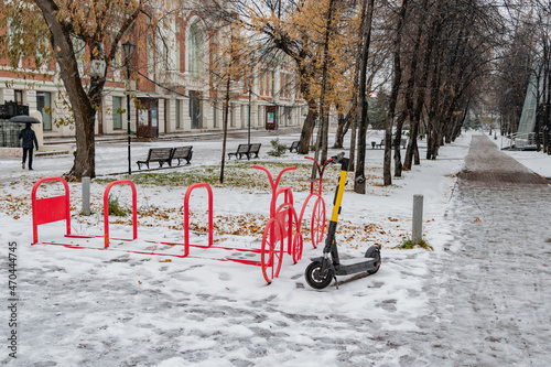 Parking of electric scooters in winter in snowy weather. The electric scooter stands on the snow. 