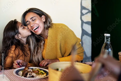 Happy Hispanic mother having tender moment with daughter while dining together with family - Parents love concept