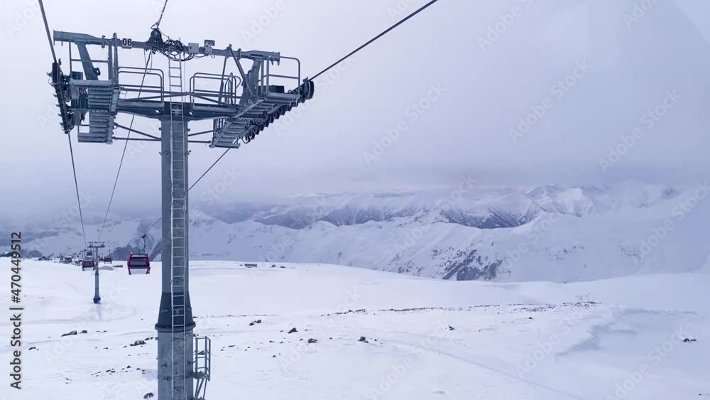 Motion of cableway lifting, beautiful landscape of empty mountains with snowy peaks around, cold winter day. View from cabin window of gondola lifting, deserted snowy hills.