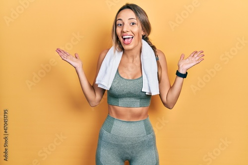 Beautiful hispanic woman wearing sportswear and towel celebrating crazy and amazed for success with arms raised and open eyes screaming excited. winner concept