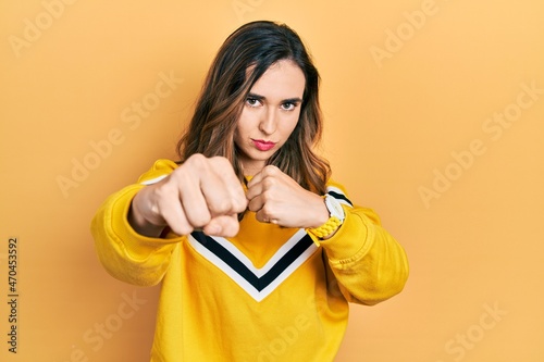 Fotografie Young hispanic girl wearing casual clothes punching fist to fight, aggressive an
