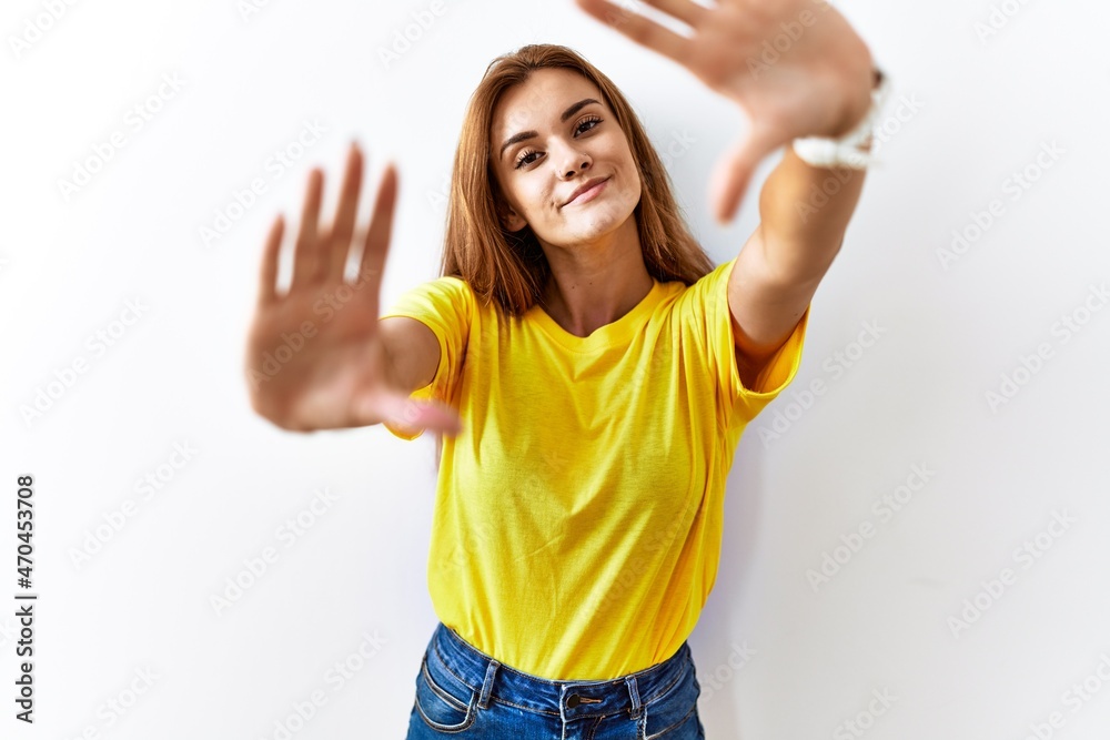 Young brunette woman standing over isolated background doing frame using hands palms and fingers, camera perspective