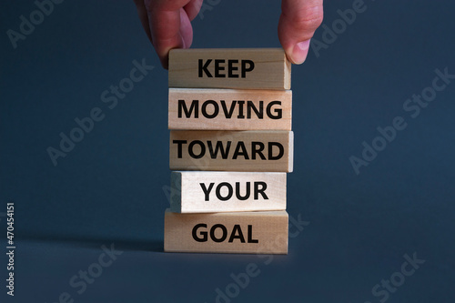 Keep moving toward your goal symbol. Wooden blocks with words Keep moving toward your goal. Businessman hand. Beautiful grey background, copy space. Business, your goal concept.