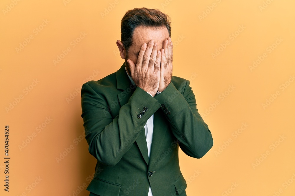 Middle age man wearing business suit with sad expression covering face with hands while crying. depression concept. Middle age man wearing business suit with sad expression covering face with hands while crying. depression concept.