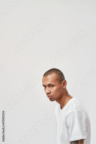 Cool young mixed race guy in casual t shirt posing isolated over white background