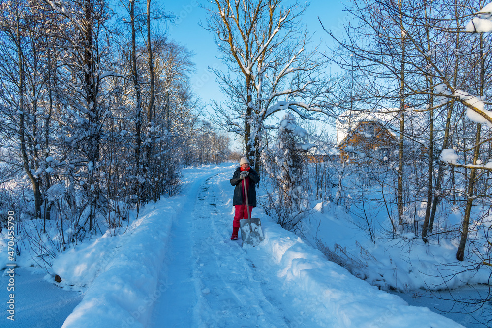 Woman cleans snowy country road.
