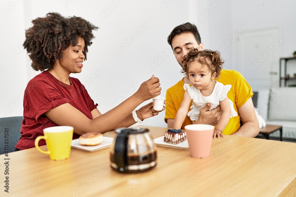 Couple and daughter having breakfast sitting on table at home Couple and daughter having breakfast sitting on table at home
