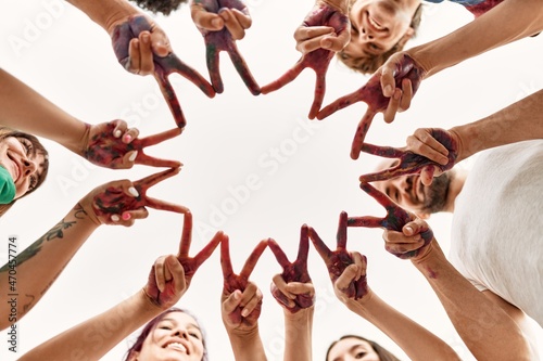 Group of young friends doing victory sign with fingers and hands together.