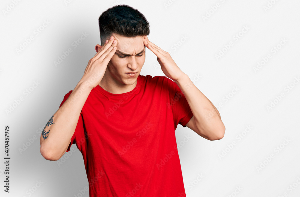Young caucasian boy with ears dilation wearing casual red t shirt with hand on head, headache because stress. suffering migraine.