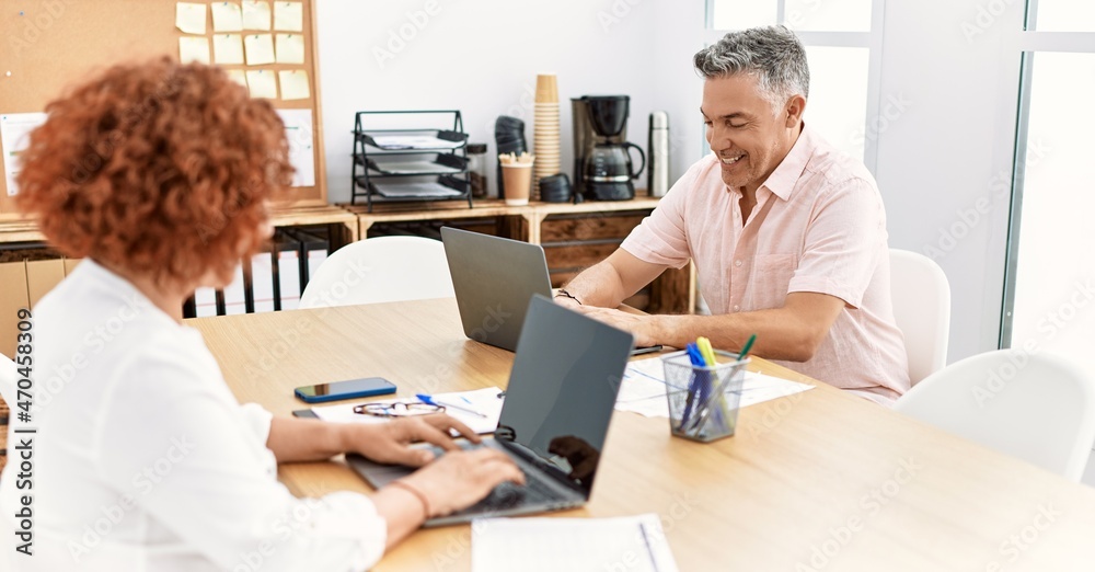 Middle age man and woman business workers using laptop working at office