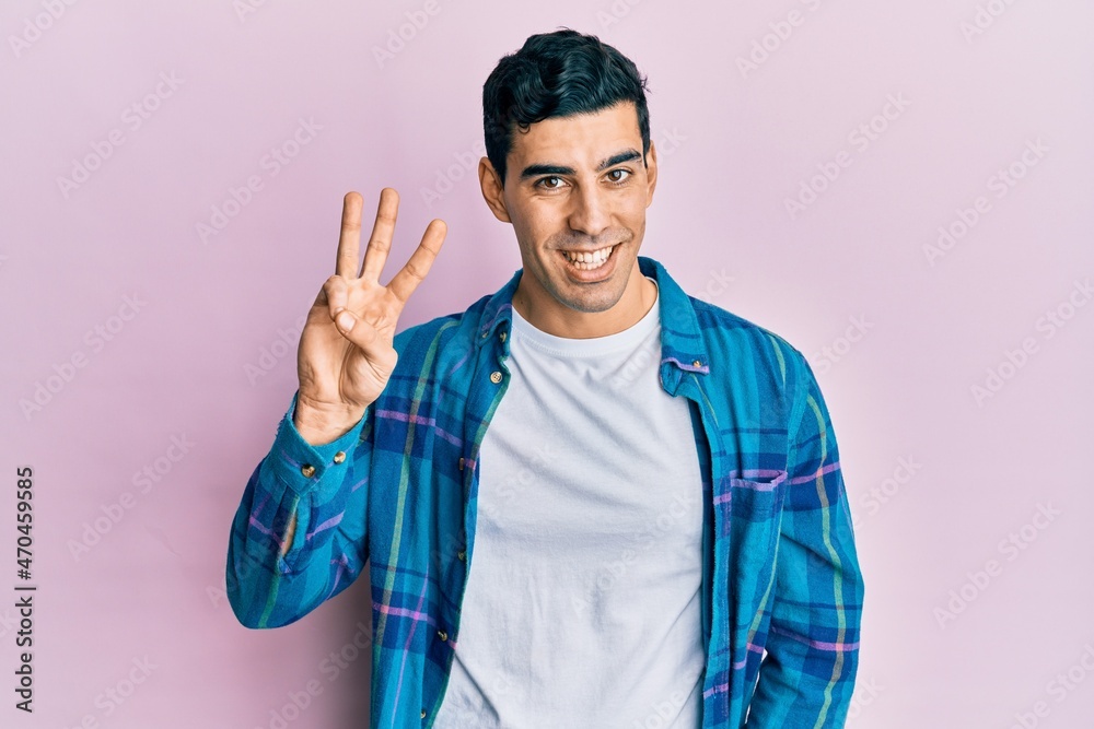 Naklejka premium Handsome hispanic man wearing casual clothes showing and pointing up with fingers number three while smiling confident and happy.