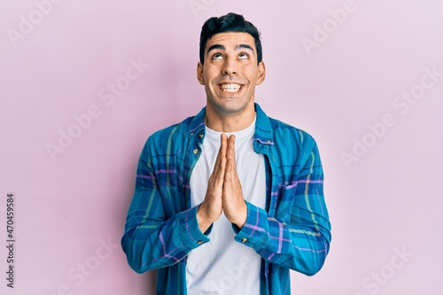 Handsome hispanic man wearing casual clothes begging and praying with hands together with hope expression on face very emotional and worried. begging.