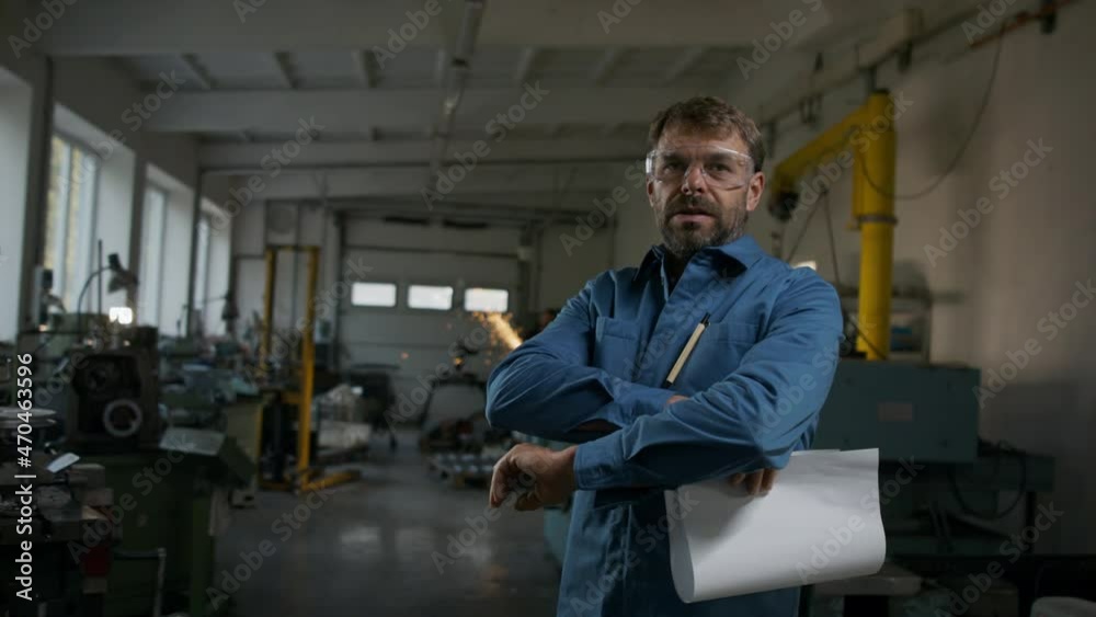 Mature industrial man working indoors in metal workshop, looking at camera. Mature industrial man working indoors in metal workshop, looking at camera.