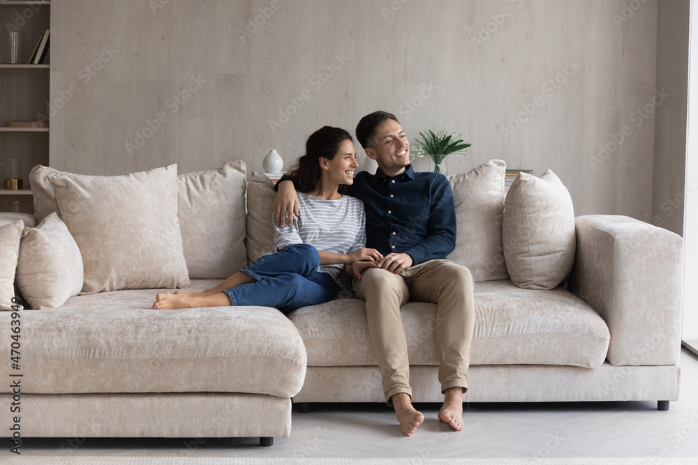 Peaceful 30s couple relaxing on comfortable couch looking out window and daydreaming about bright future at new own house. Bank loan and medical insurance, modern fashionable furniture shop ad concept Peaceful 30s couple relaxing on comfortable couch looking out window and daydreaming about bright future at new own house. Bank loan and medical insurance, modern fashionable furniture shop ad concept