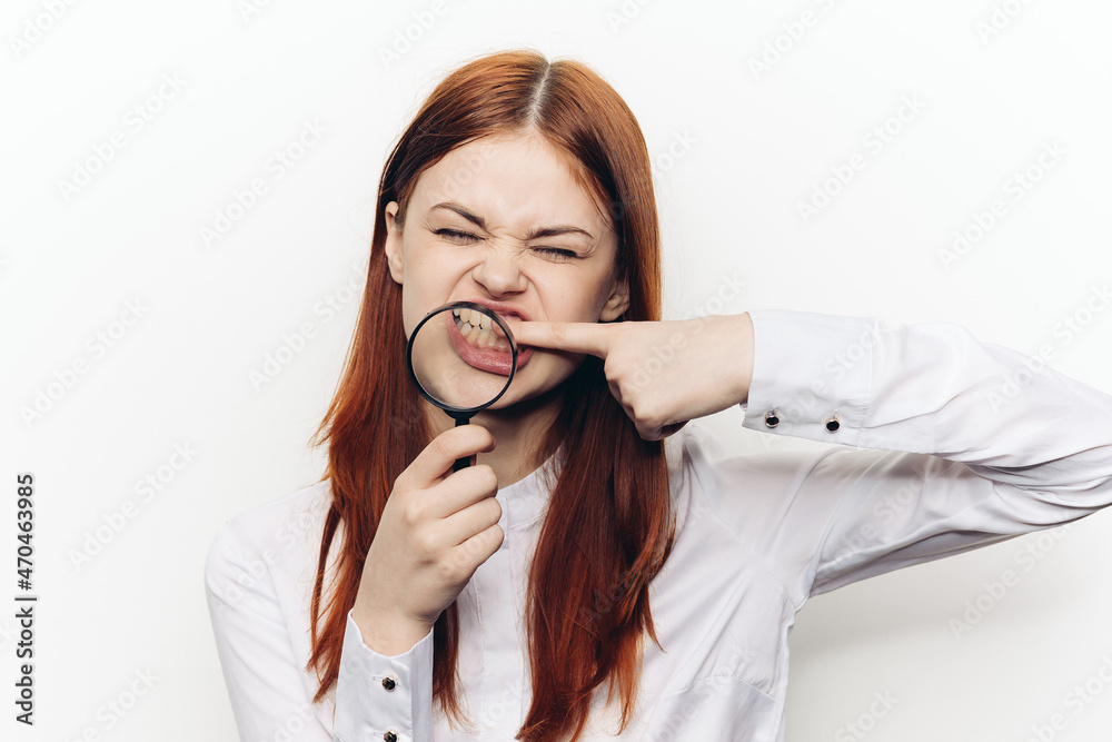 cheerful red-haired woman holding a magnifying glass near her face cheerful red-haired woman holding a magnifying glass near her face