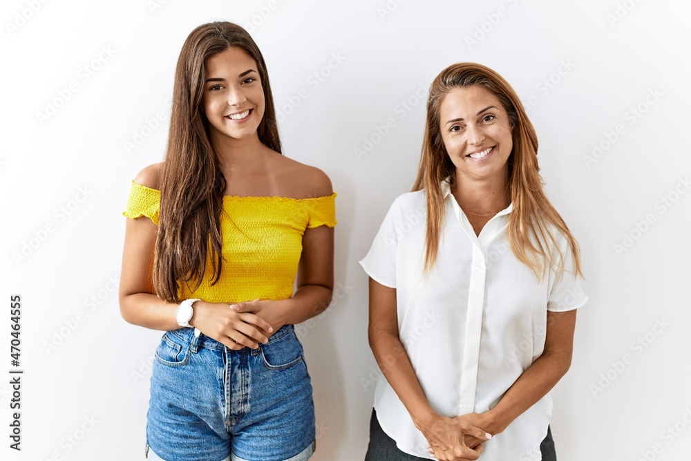 Mother and daughter together standing together over isolated background with hands together and crossed fingers smiling relaxed and cheerful. success and optimistic