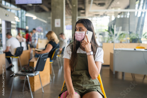 Young woman in face mask talking on mobile phone at indoor.