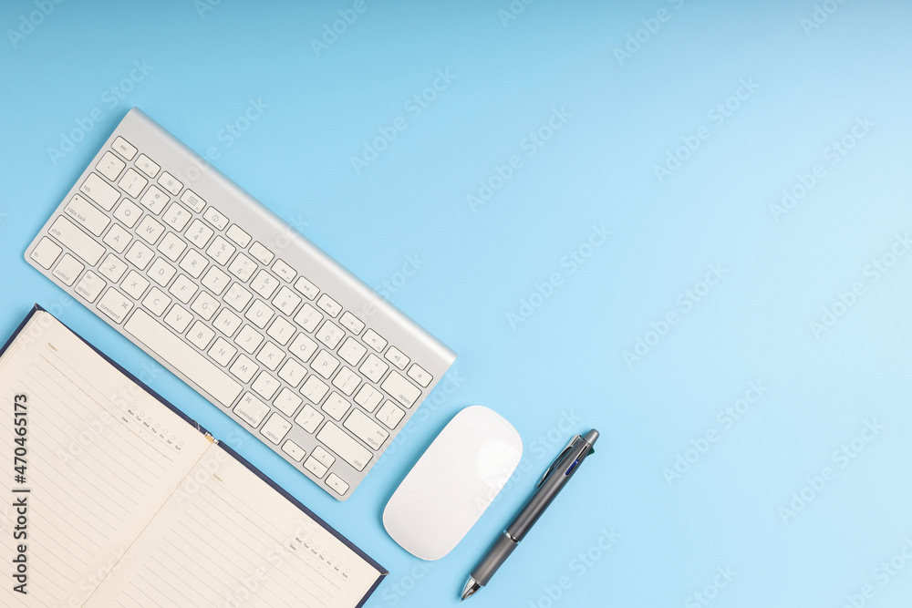 Top view office desk with keyboard, pen, mouse, and notebook. Blue table with the gadget for business put on the table neat. Empty blue background copy space. Top view office desk with keyboard, pen, mouse, and notebook. Blue table with the gadget for business put on the table neat. Empty blue background copy space.