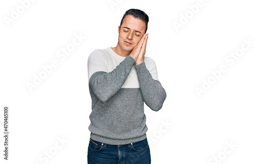 Handsome young man wearing casual winter sweater sleeping tired dreaming and posing with hands together while smiling with closed eyes.
