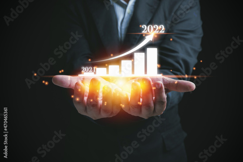 Businessman holding graph business, growth corporation from previous years 2021 to the year 2022 on hands. Risk assessment and set strategy for business to the future growth year 2022.