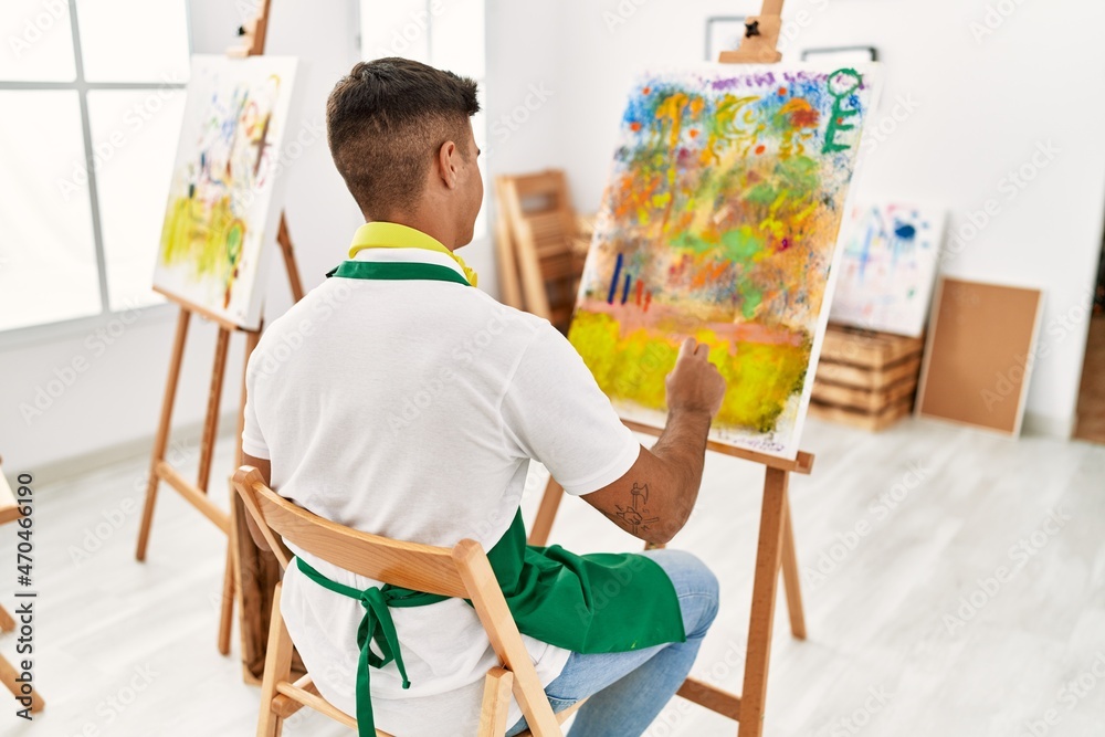 Fototapeta premium Young hispanic man on back view drawing at art studio
