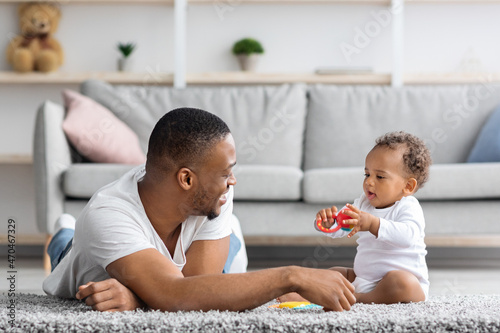 Shared Parental Leave. Young Black Father Playing With Little Baby At Home photo