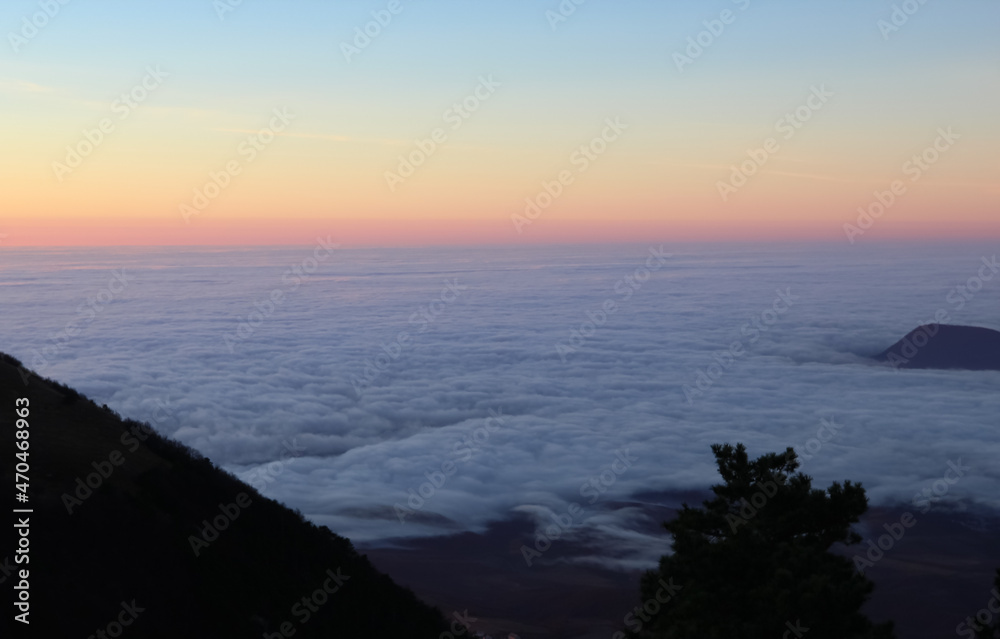 Landscape of the rising sun in the mountains. Red reflexes from the sun on the clouds in the valley. Areal view Landscape of the rising sun in the mountains. Red reflexes from the sun on the clouds in the valley. Areal view