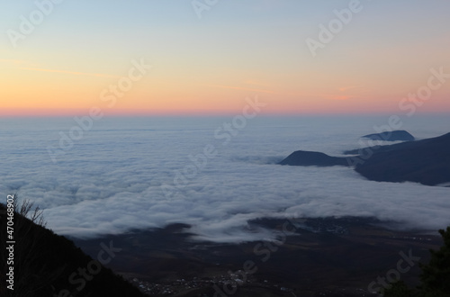 Landscape of the rising sun in the mountains. Red reflexes from the sun on the clouds in the valley. Areal view