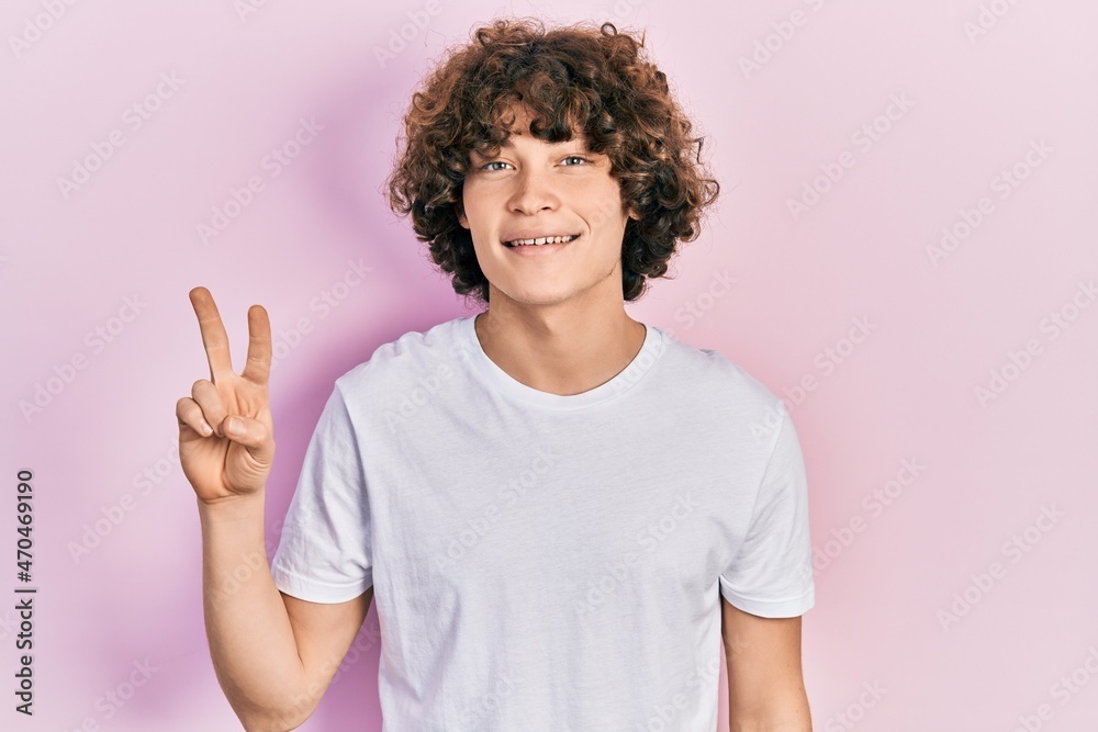 Handsome young man wearing casual white t shirt showing and pointing up with fingers number two while smiling confident and happy. Handsome young man wearing casual white t shirt showing and pointing up with fingers number two while smiling confident and happy.