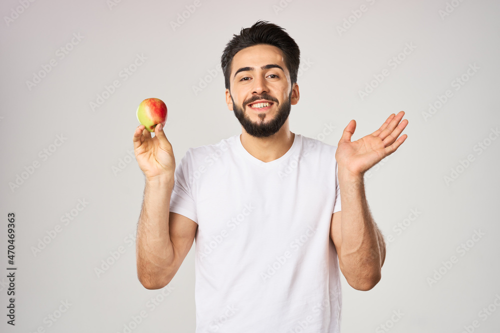 Cheerful man in a white t-shirt with an apple in the hands of health fruits Cheerful man in a white t-shirt with an apple in the hands of health fruits