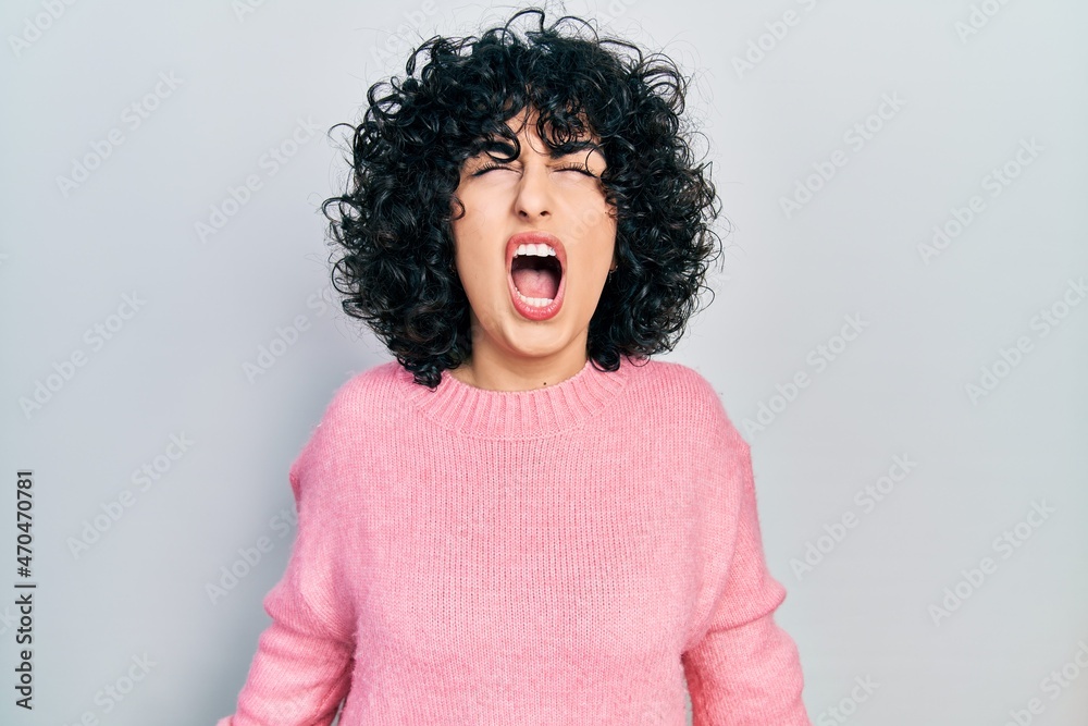 Young middle east woman wearing casual clothes angry and mad screaming frustrated and furious, shouting with anger. rage and aggressive concept. Young middle east woman wearing casual clothes angry and mad screaming frustrated and furious, shouting with anger. rage and aggressive concept.
