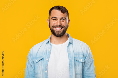 Smiling happy mature european man looking at camera, isolated on yellow background, free space