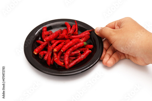 hand holding peeled red chili in black plate on white background