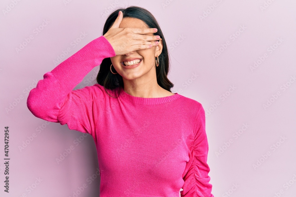 Young hispanic woman wearing casual clothes smiling and laughing with hand on face covering eyes for surprise. blind concept. Young hispanic woman wearing casual clothes smiling and laughing with hand on face covering eyes for surprise. blind concept.