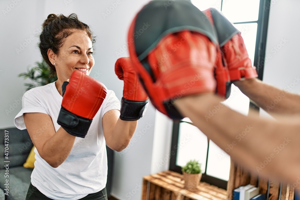 Middle age hispanic couple smiling happy training boxing at home.