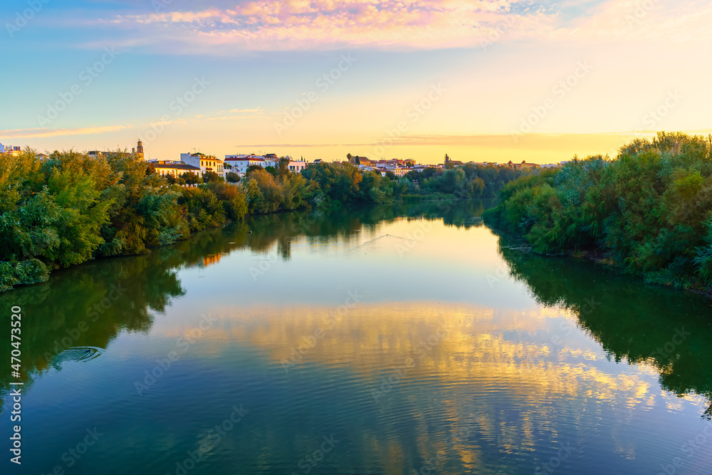 Guadalquivir river at sunrise on a calm day and golden atmosphere in the city of Cordoba Spain.