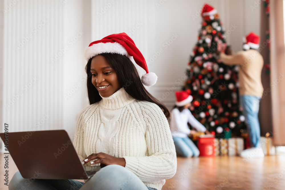 Happy black lady using laptop on Xmas eve Happy black lady using laptop on Xmas eve