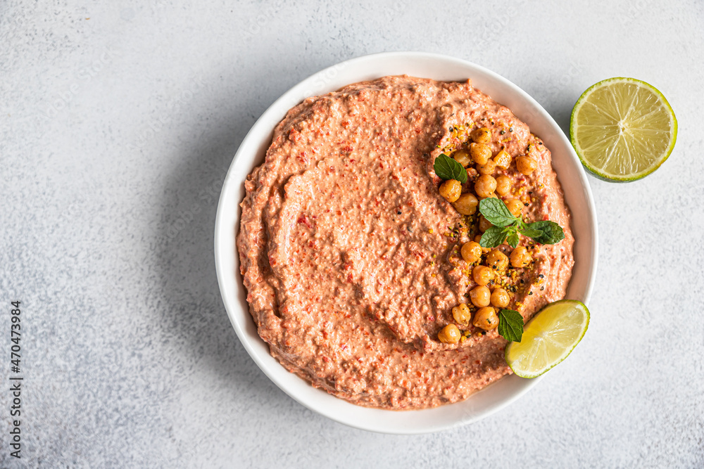Roasted red pepper hummus garnish with mint and lime. Mashed chickpeas with red bell pepper, lime and mint. Vegetarian snack. Top view. Roasted red pepper hummus garnish with mint and lime. Mashed chickpeas with red bell pepper, lime and mint. Vegetarian snack. Top view.