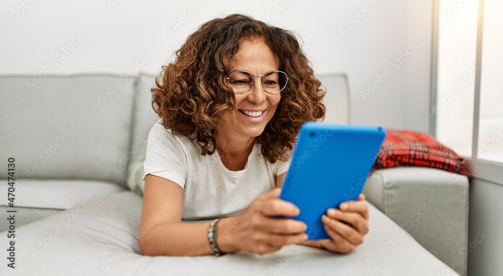 Middle age hispanic woman smiling confident using touchpad at home Middle age hispanic woman smiling confident using touchpad at home